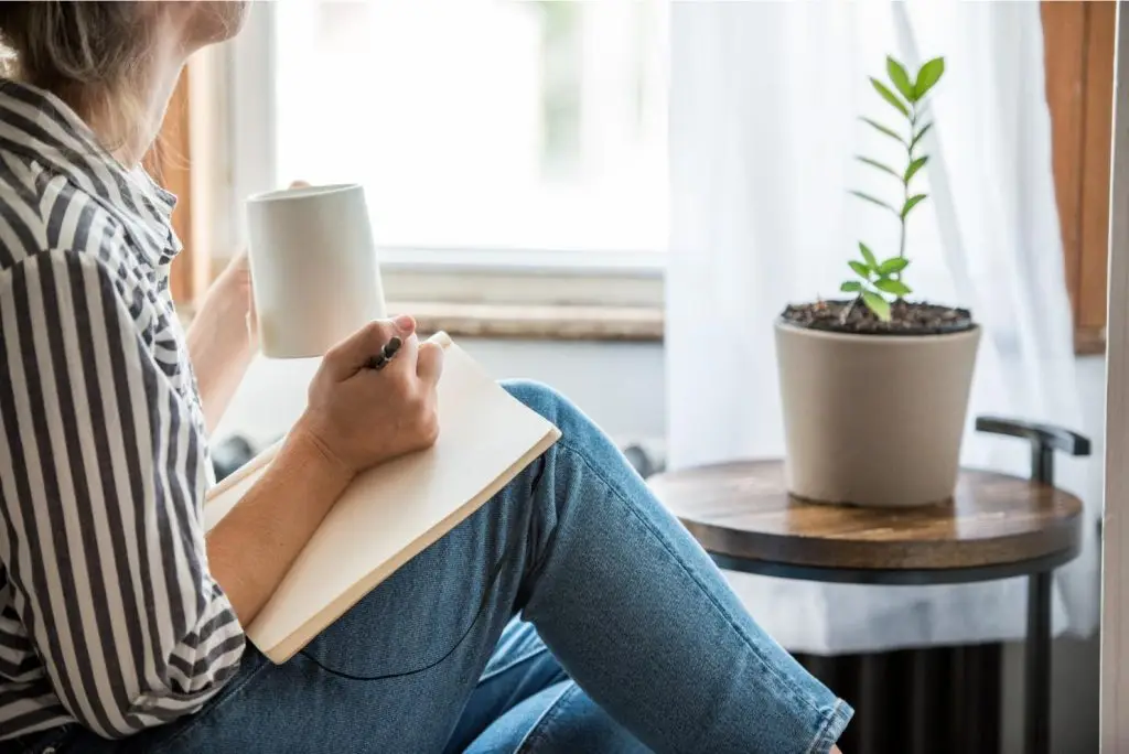 girl writing in her journal and drinking tea. This is a healthy practice for those who experience anxiety.