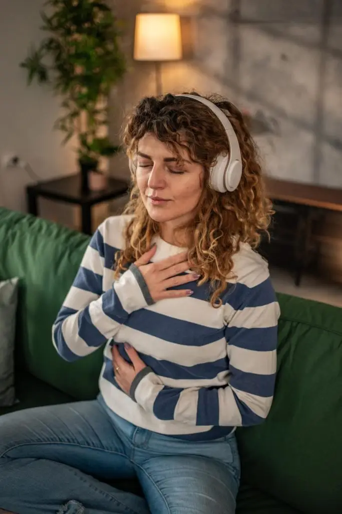 A young woman practices guided meditation in the living room, the concept of healthy living, inner peace and balance
