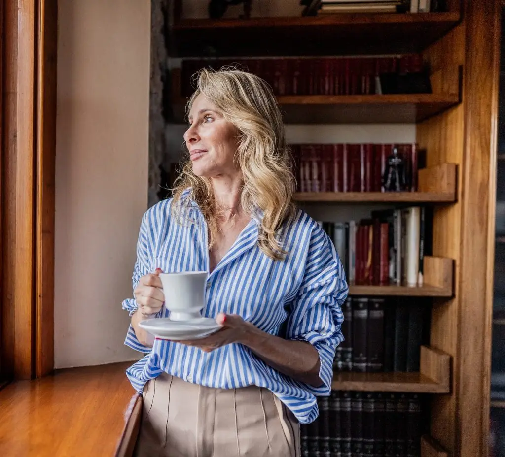 Mature woman contemplating while looking through the window at home