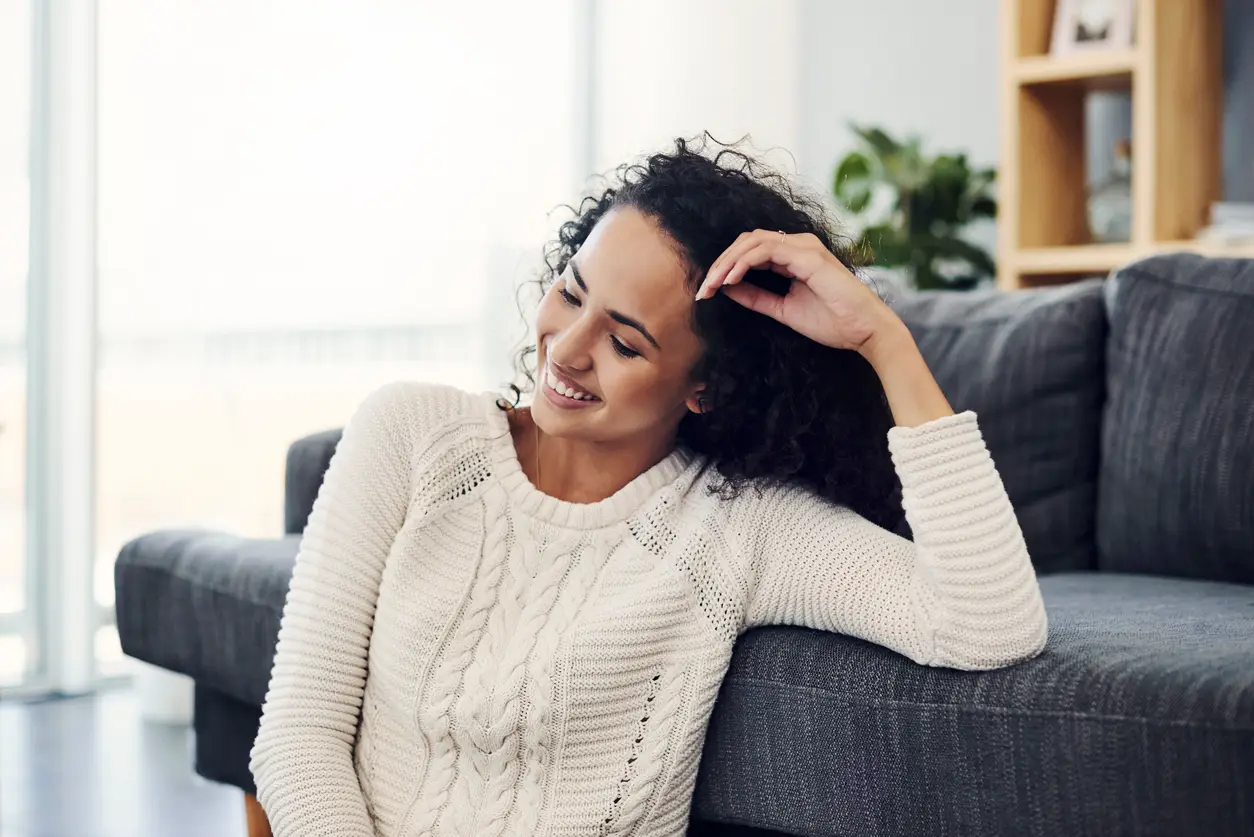 Cropped shot of an attractive young woman smiling while sitting on the floor in her living room